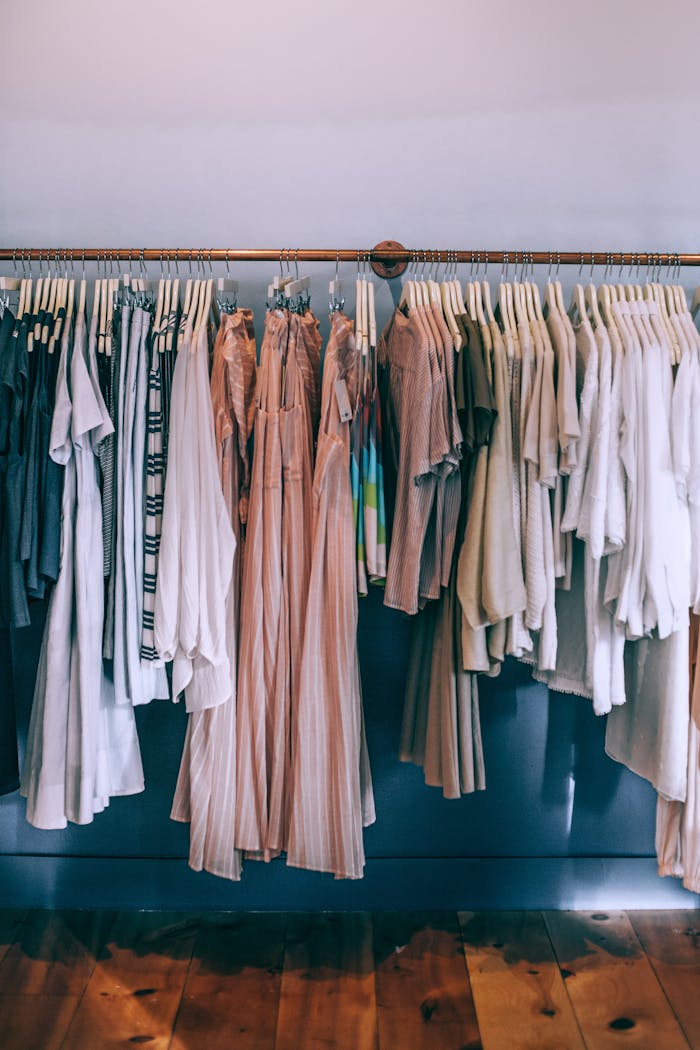 A stylish array of neutral-toned clothing hanging on racks in a boutique.