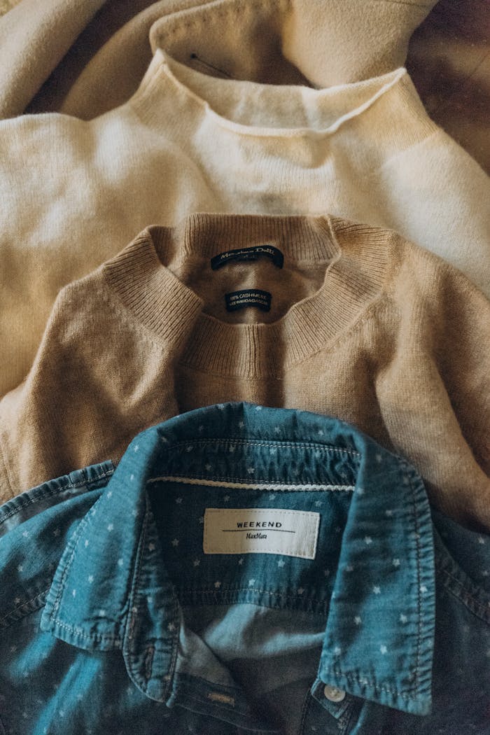 A selection of textured sweaters and a denim shirt in earthy tones.